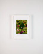 Bright and dark green moss wall with coloured flowers and wood sticks fine art print on a white wall in frame