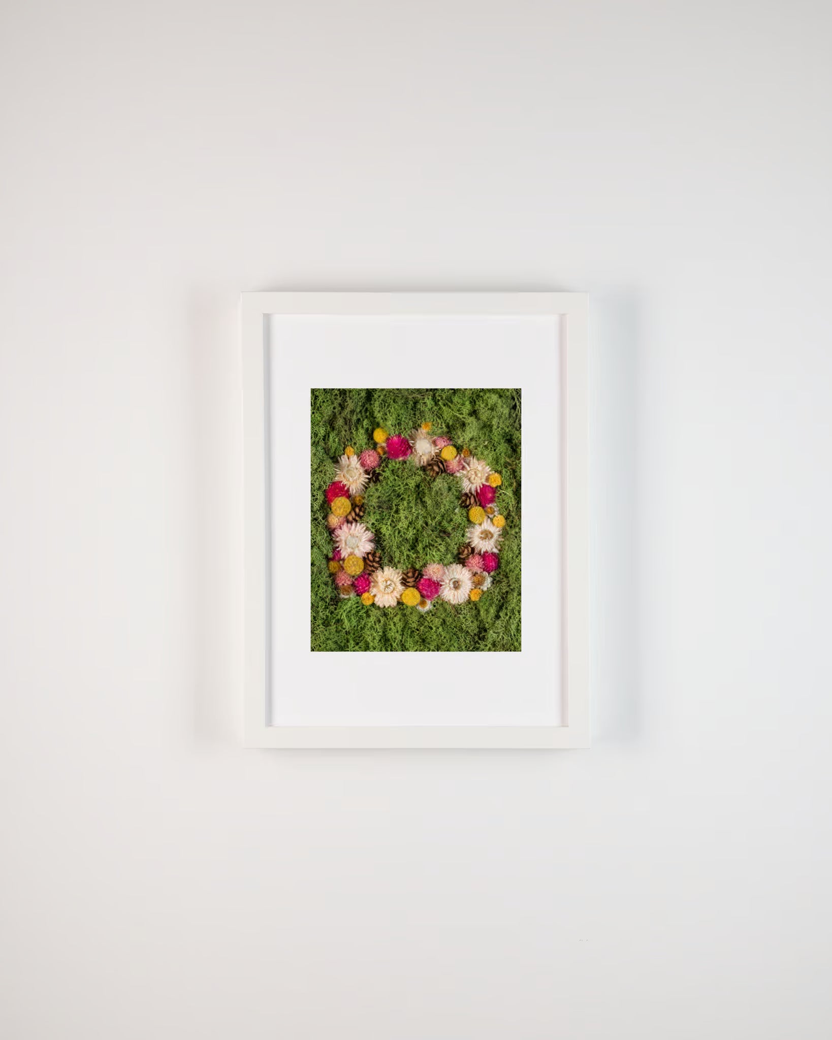 Floral wreath with pink, yellow, and white flowers on a green moss background fine art print