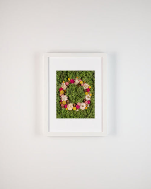 Floral wreath with pink, yellow, and white flowers on a green moss background fine art print