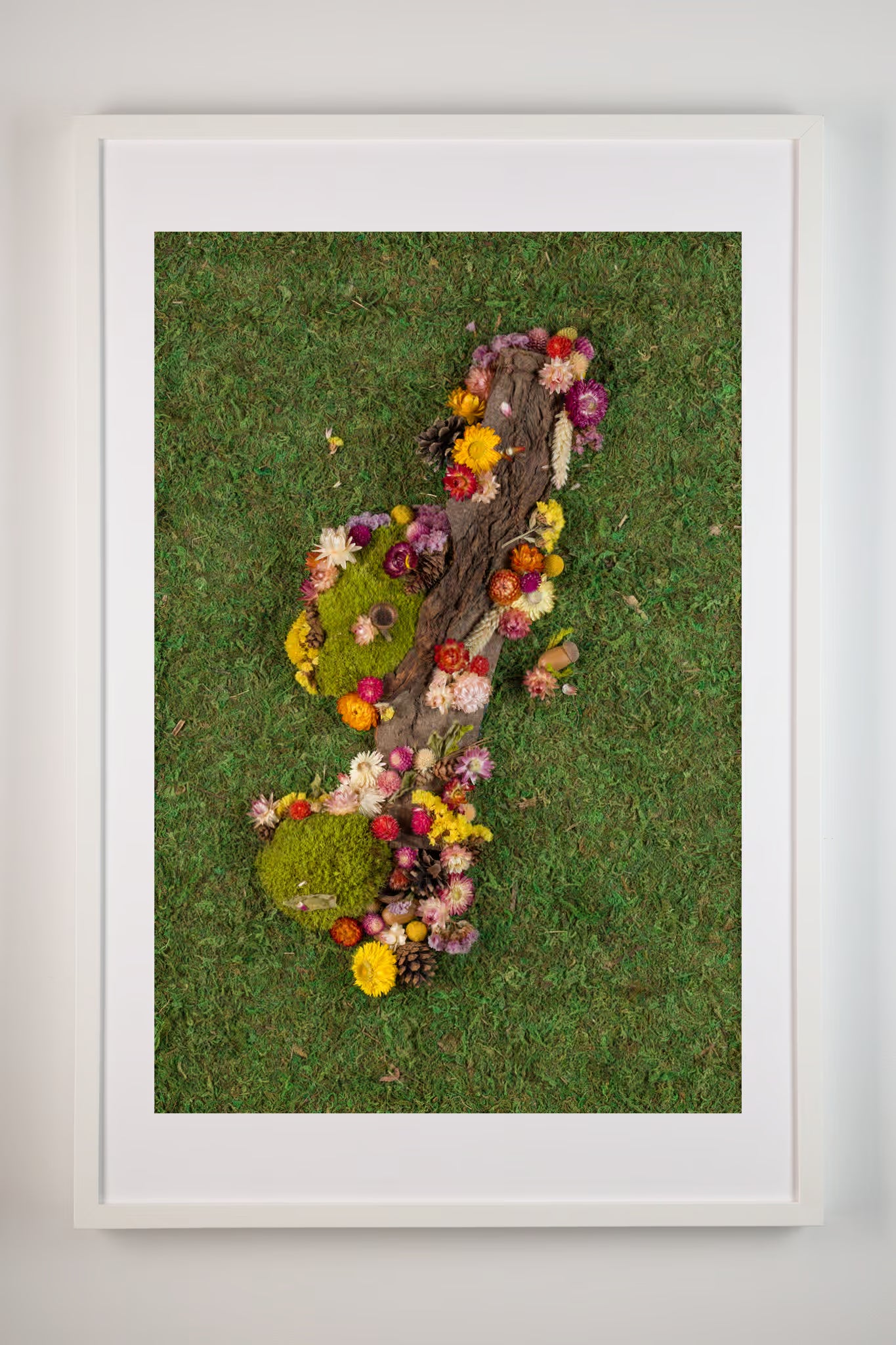 Green forest moss wall with wood bark and colourful flowers fine art print shown in white frame