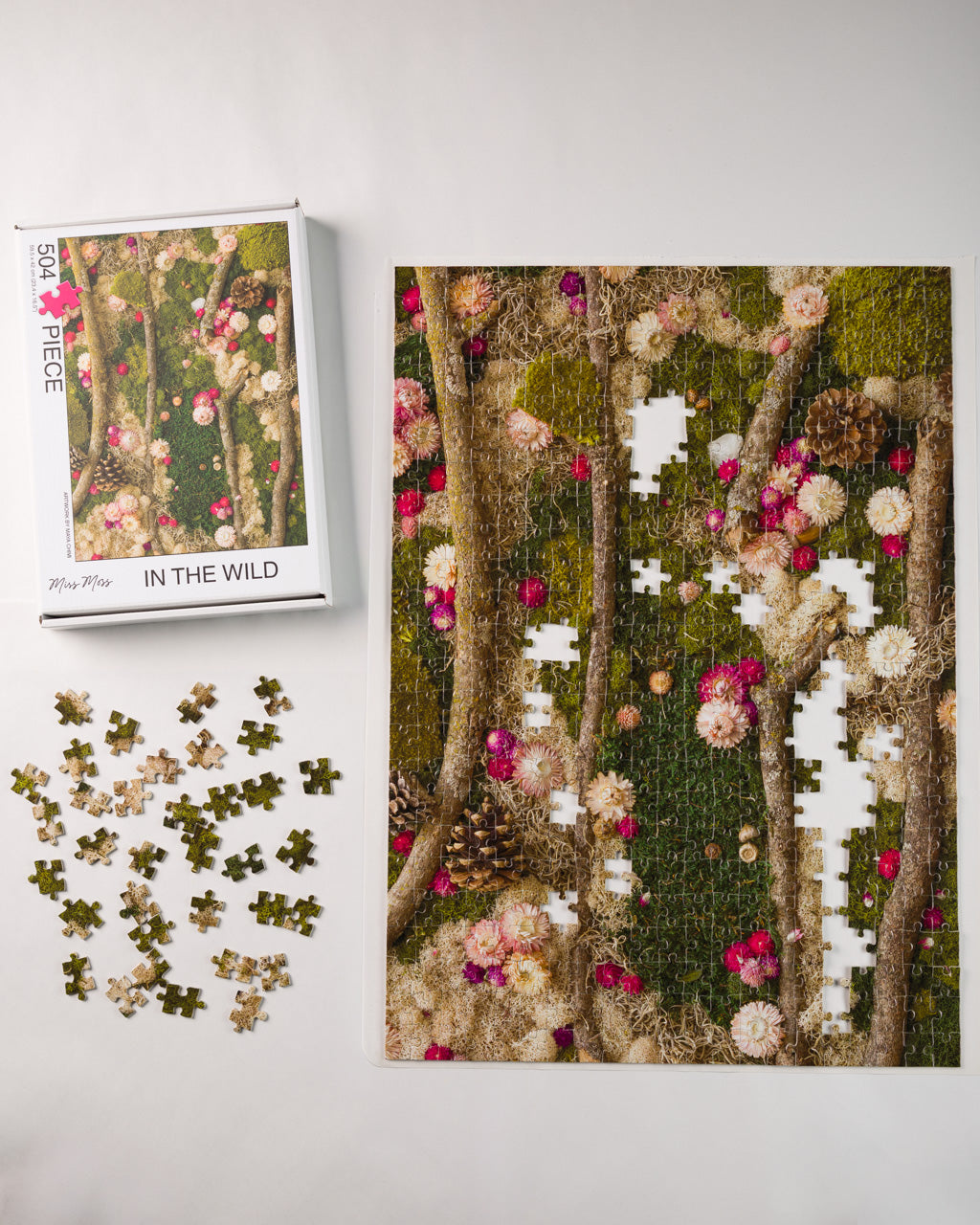 504 piece jigsaw puzzle of green moss wall with flowers and wood in nature being assembled