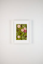 Framed fine art print of pink flowers and pinecones on green moss